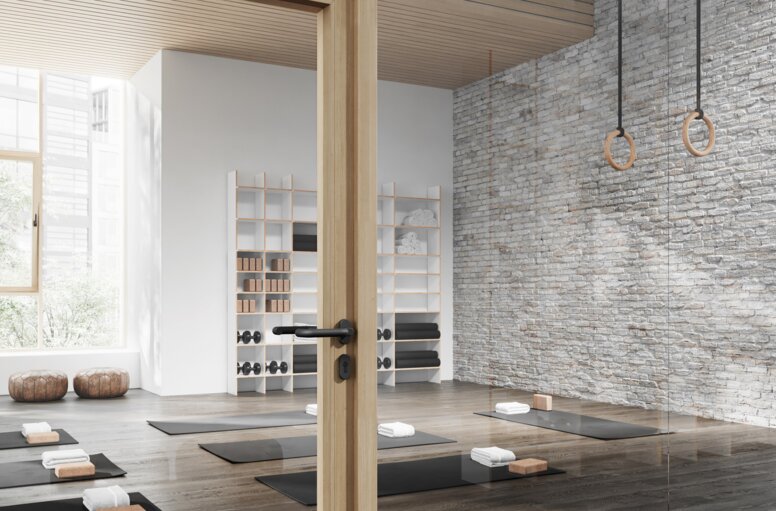 Glastür mit Holzrahmen zu einem Yoga-Raum ausgestattet mit HEWI Türgriff 111 in Anthrazit matt aus Polyamid