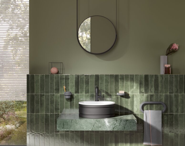 HEWI Range 477 Interior A round washbasin set on a green marble vanity unit with a black tap and towel holder, with a round mirror above it