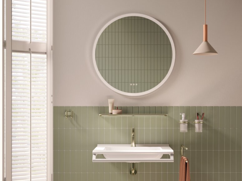 An accessible washbasin with a front-mounted support rail and a stool against a green tiled wall