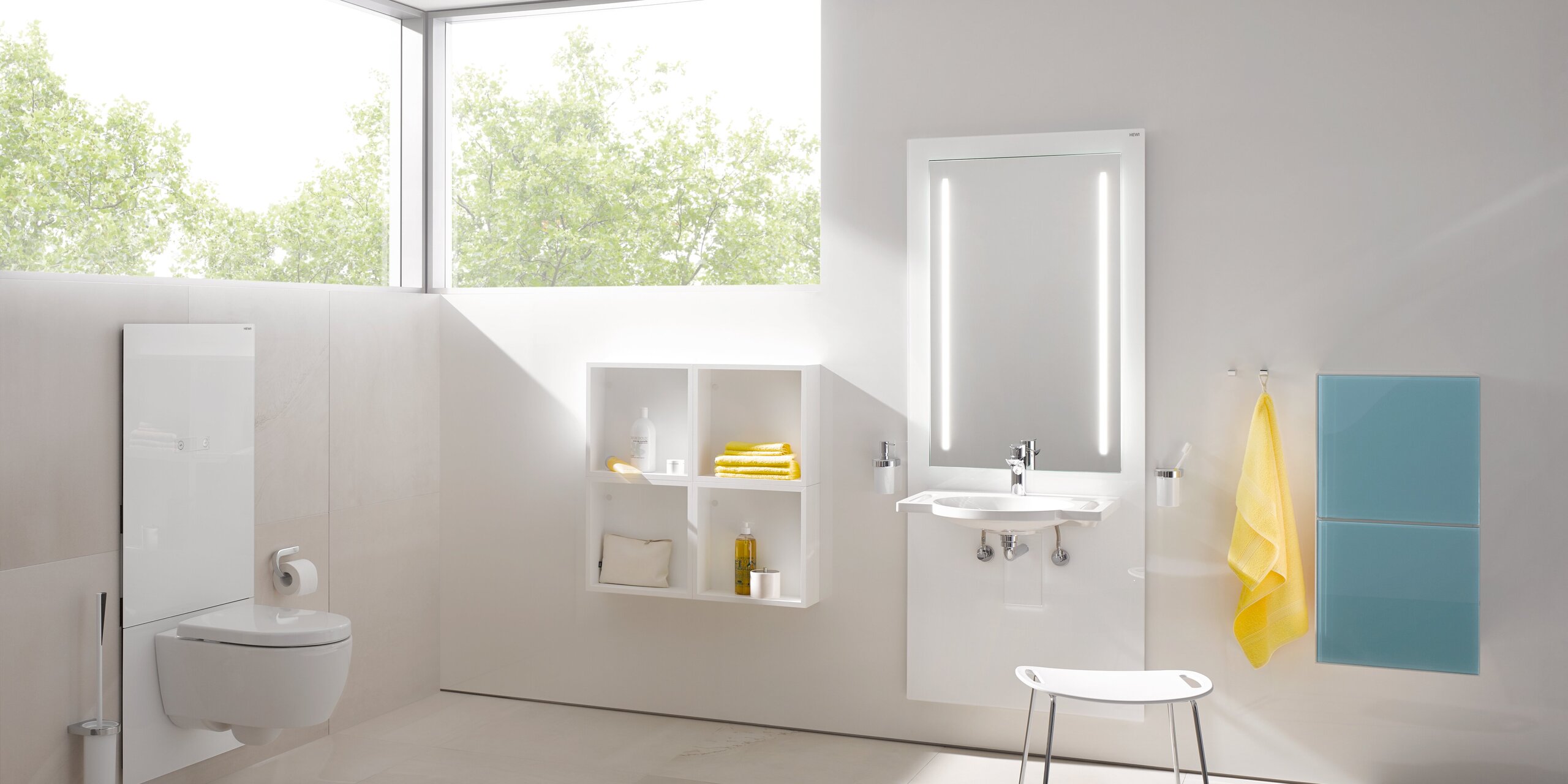 Weißes WC-Modul in einem hellen Badezimmer mit beleuchtetem Spiegel über dem Waschbecken, davor ein Hocker mit weißer Sitzfläche