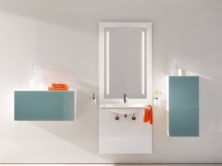 HEWI S 50 Washbasin Module White washbasin module with a rectangular mirror and two taps against a light-coloured wall, flanked by a light blue wall cabinet on the left and a tall light blue cabinet on the right