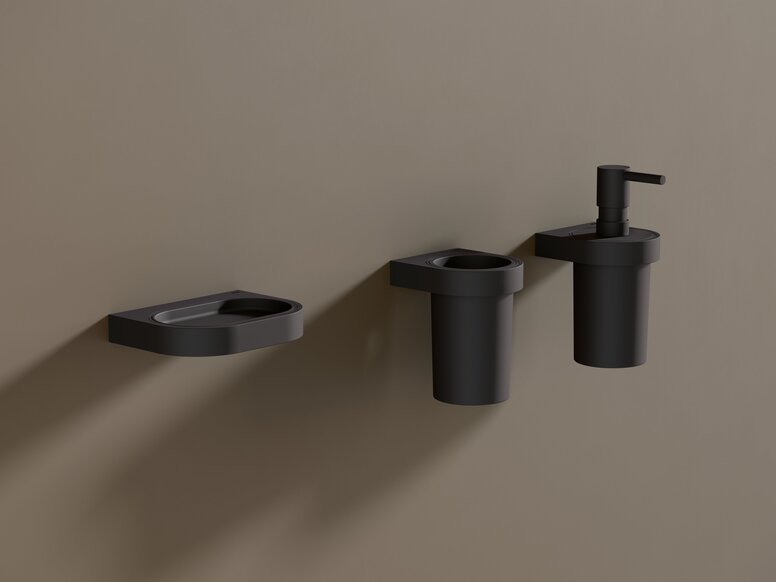 HEWI System 800 Ablage, Becher, Seifen- oder Desinfektionsmittelspender Schwarze pulverbeschichtete Seifenablage sowie ein Becher und ein Seifenspender an brauner Wand