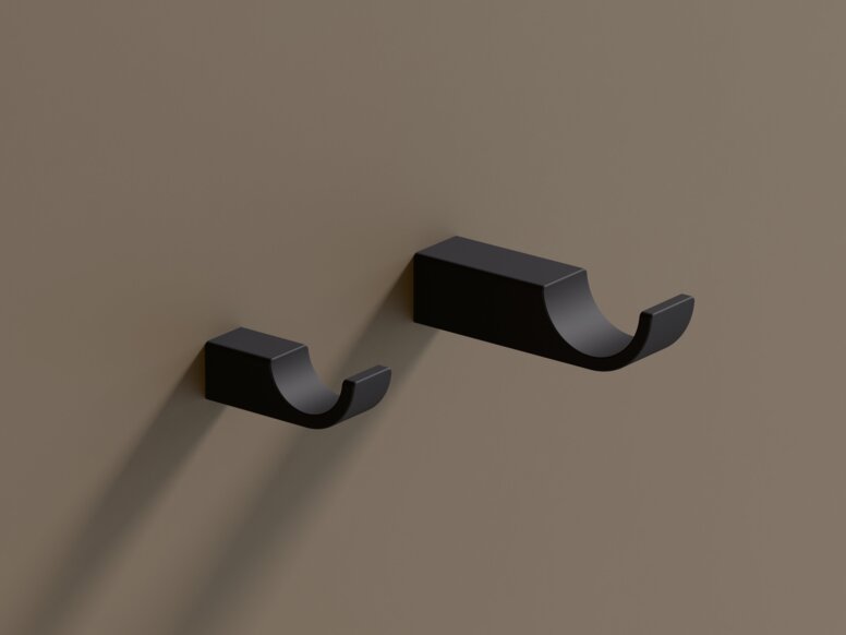 Two black powder-coated hooks of different lengths mounted side by side on a brown wall