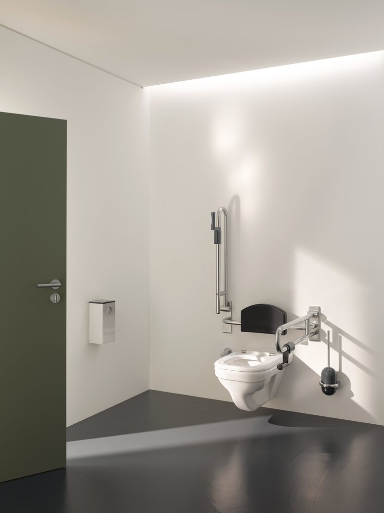 HEWI Range 805 Interior WC with a hinged backrest and two hinged support handles fitted on the left and right in the area of accessibility against a white wall
