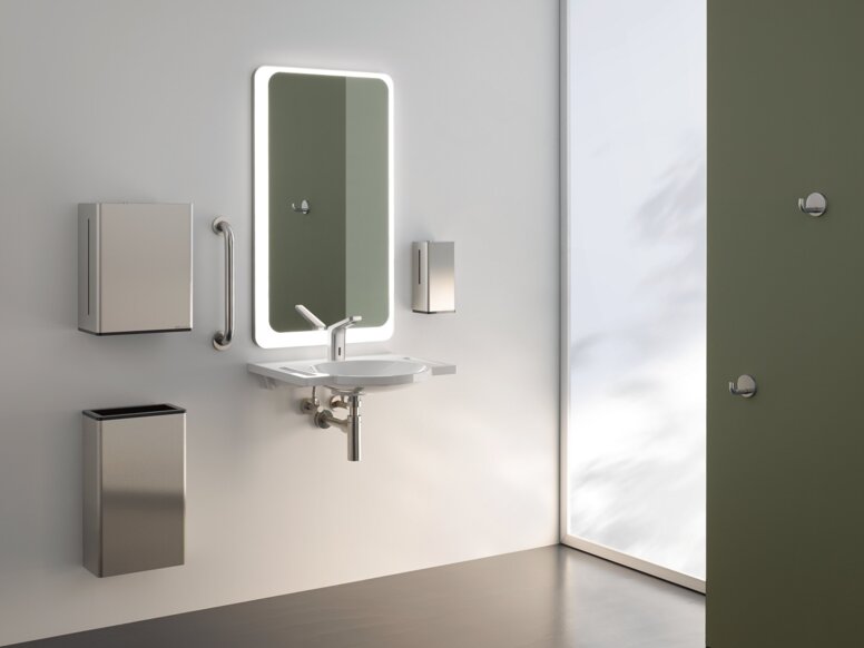 HEWI Serie 805 Interieur Beleuchteter Spiegel, darunter Handwaschbecken mit Papierspender und Abfalleimer an weißer Wand
