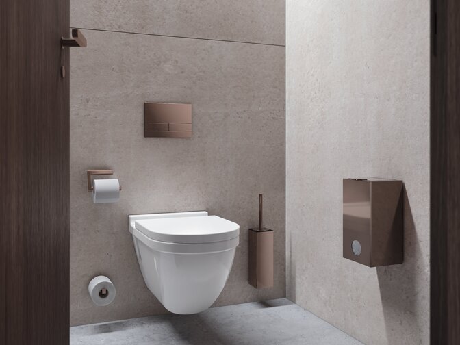 Wandhängendes WC mit Toilettenbürste und WC-Papierhalter mit Druckspüler in Kupfer-Optik an beigefarbener Betonwand