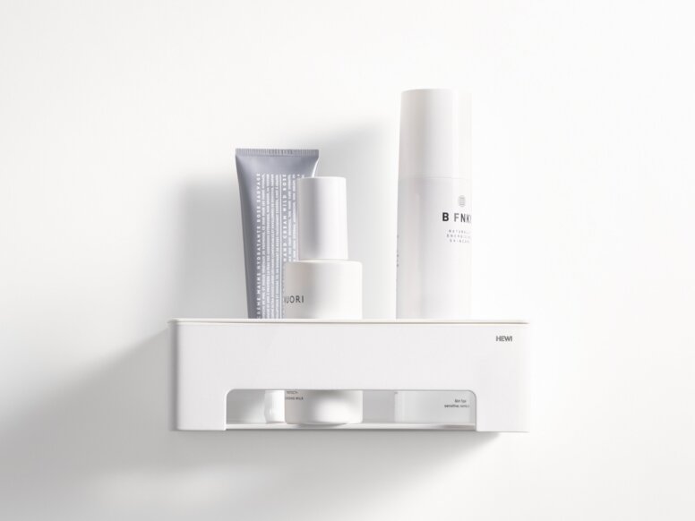 HEWI System 900 Duschkorb Weißer wandhängender Duschkorb mit Ablagefläche und offenem Fach, bestückt mit Pflegeprodukten an weißer Wand