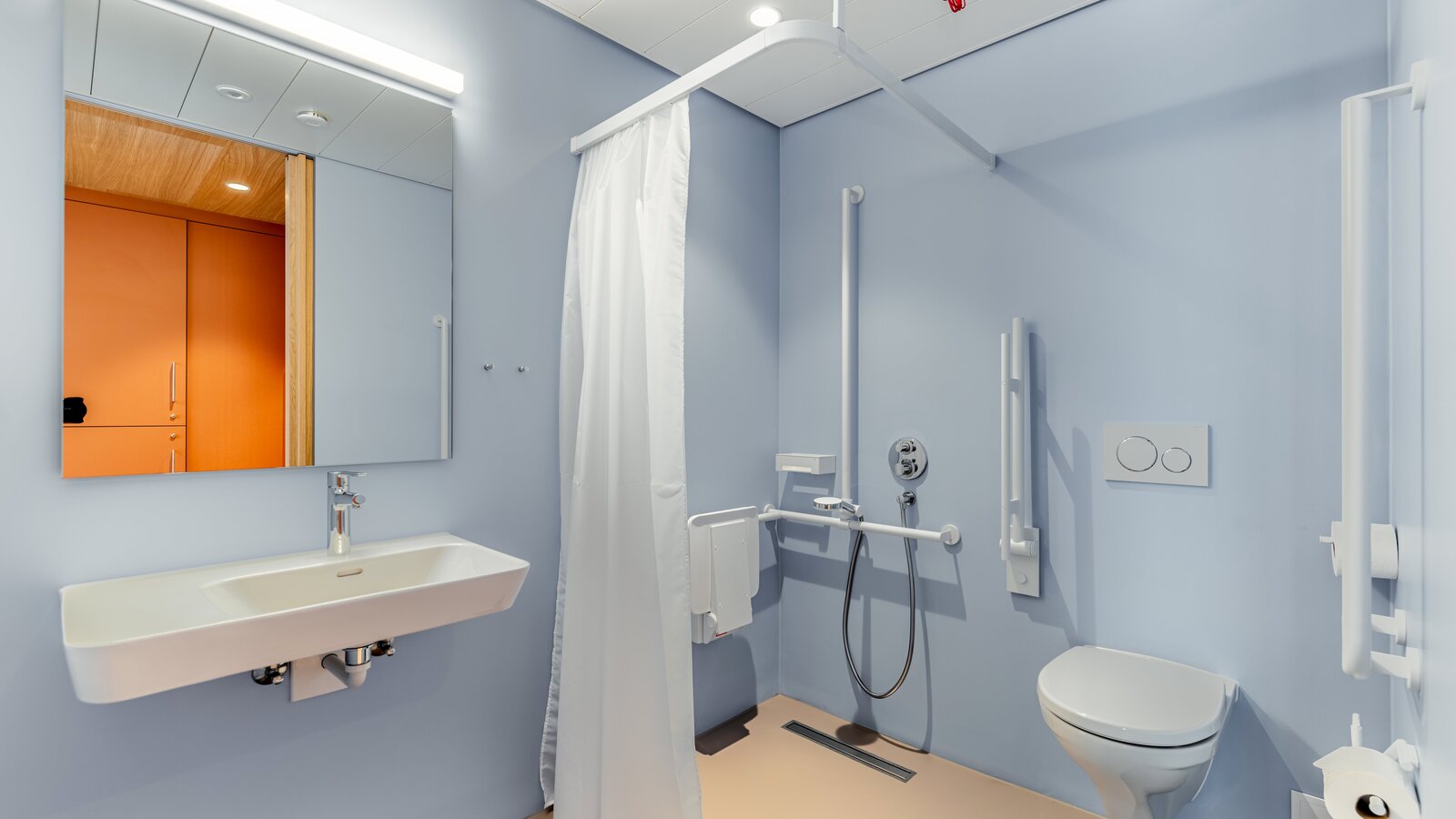 Bathroom at Haslibrunnen in Switzerland Accessible bathroom with a wall-mounted WC, hinged support rail and folding shower seat