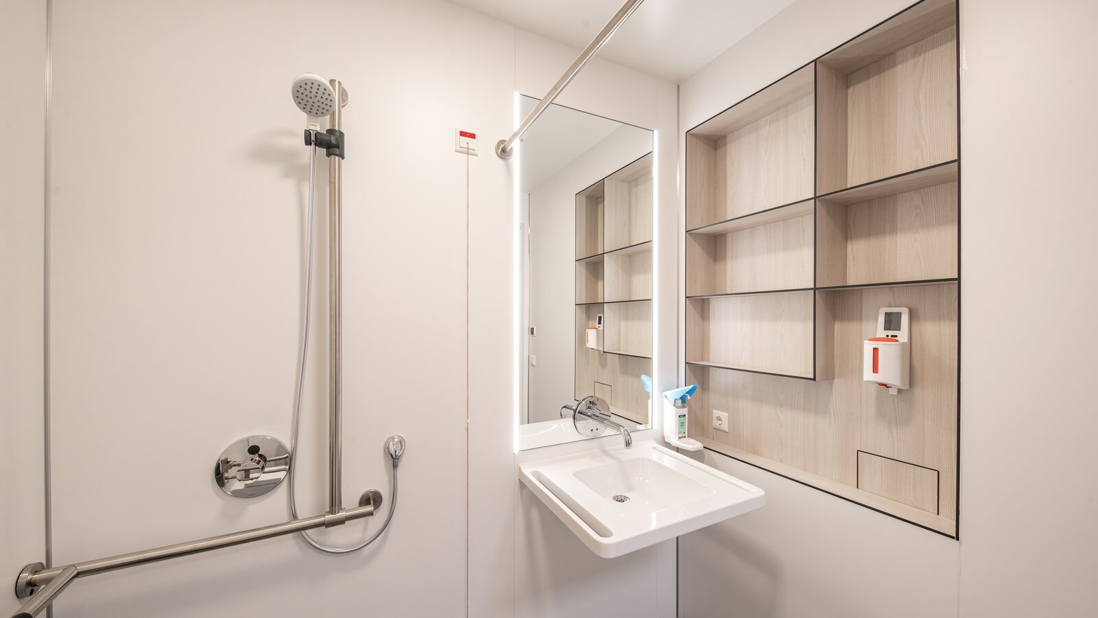 Patientenbad mit Waschplatz und Duschbereich ausgestattet mit HEWI Waschtisch und Brausehalter in Edelstahl